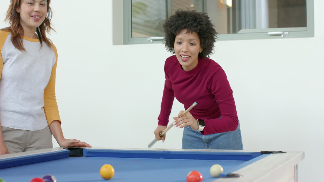 Woman following supportive tips leaning over blue pool table lining up cue shot in game room