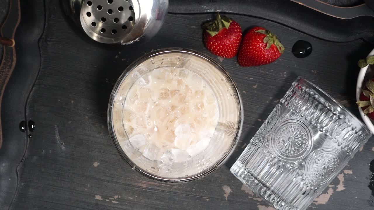 Pink cocktail drink with strawberry liqueur, vanilla vodka and cream. Party drink with strawberries. Fruit cocktail with fresh strawberries as a garnish. Cold and refreshing adult drink.