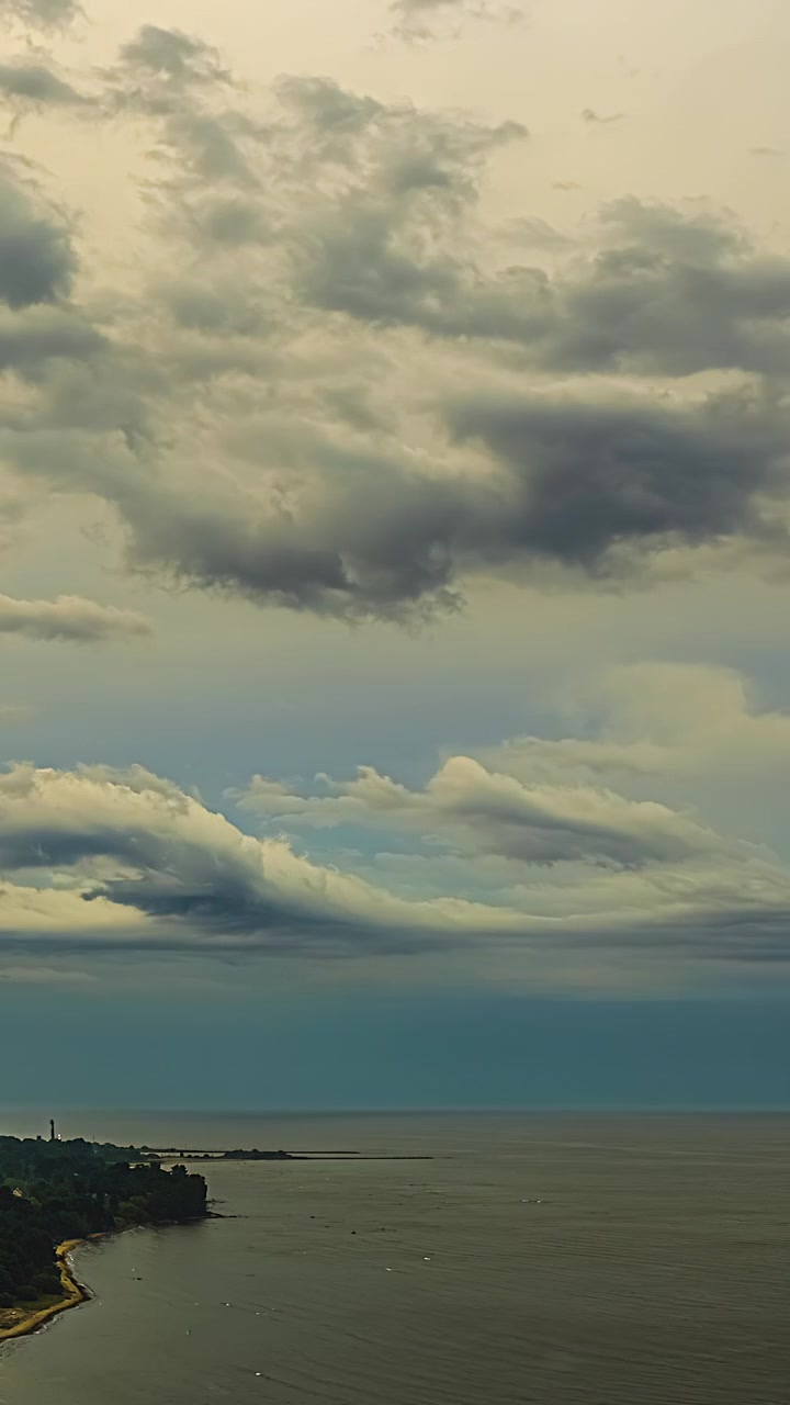 Clouds move swiftly over a coastal landscape as daylight shifts near shoreline cliffs