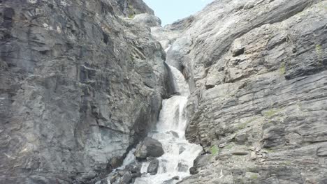 Filmische-Luftaufnahme-Eines-Kleinen-Wasserfalls,-Der-Einen-Großen-Berg-Hinunterfließt