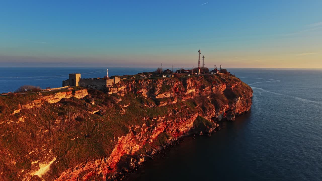 Splendida vista costiera al tramonto con scogliere e acqua dell'oceano a fuoco