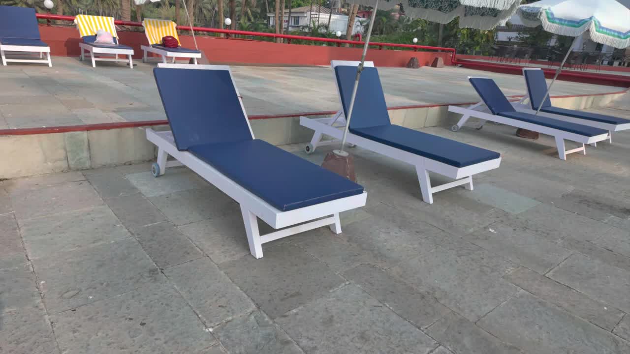 4K video of approaching a blue sun lounge then drop a white towel on it