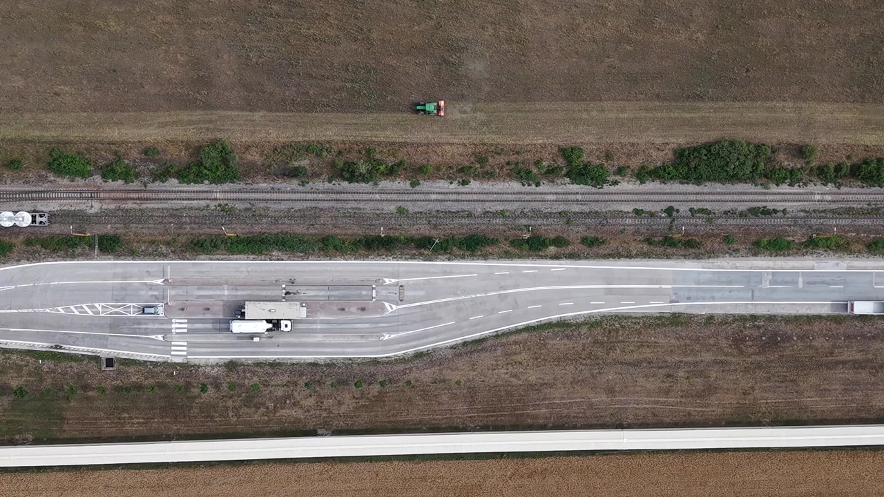 An aerial view showcases various transportation modes including roads, railways, and agricultural fields, highlighting interconnectedness in rural logistics and development.