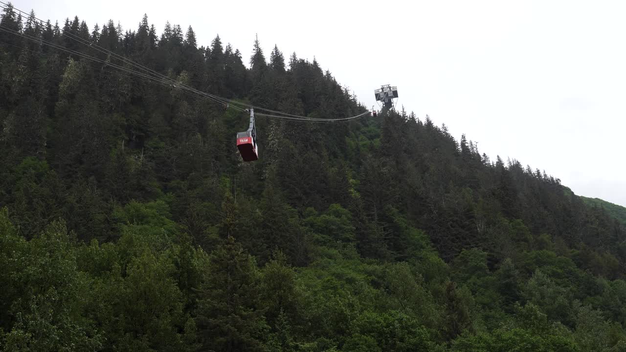 Goldbelt Tram cabin in Juneau, Alaska, ascends on a cloudy and rainy day.