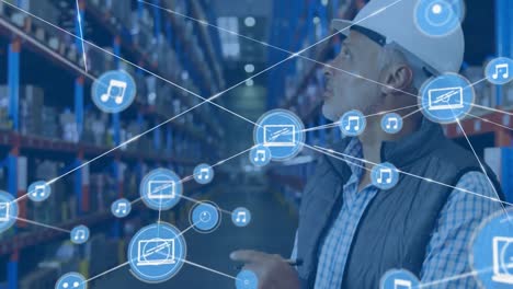 animation of network of connections with icons over man writing on clipboard in warehouse