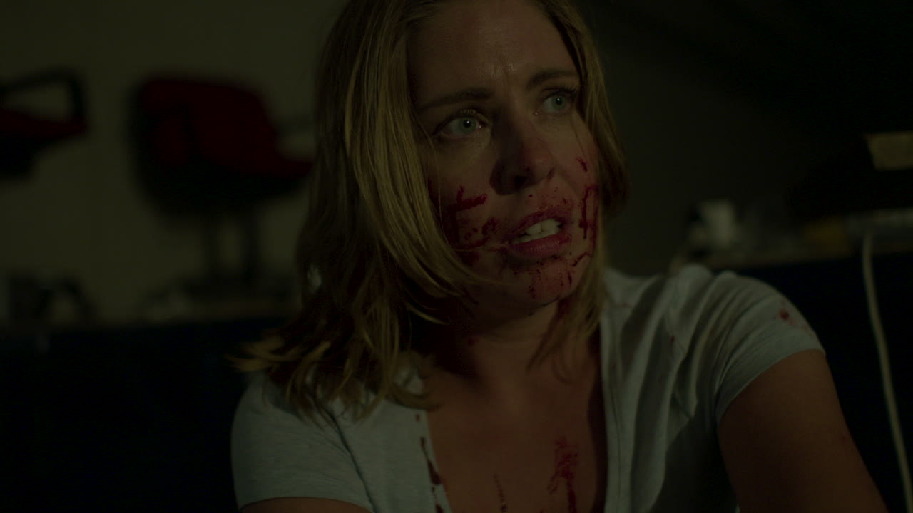 Terrified and blood covered woman in scary basement