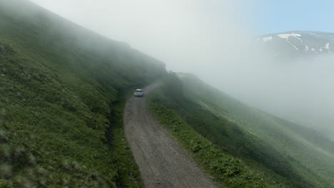 AERIAL---Car-driving-down-the-Tskhratskaro-Pass,-Georgia,-rising-forward-shot