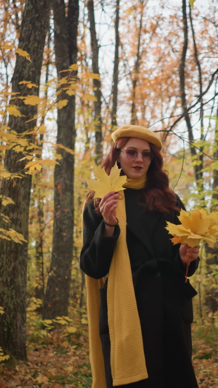 una dama elegante con una boina amarilla y un largo abrigo negro se pasea por un denso bosque de otoño, sosteniendo hojas amarillas vibrantes, creando una pintoresca escena de otoño
