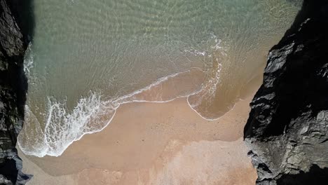 Rocky-Cove-with-Beach-and-Ocean-Waves,-Top-Down-Aerial-View-in-Slow-Motion,-Cornwall,-UK