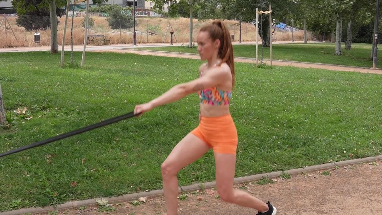 Una donna in un parco si allena con fasce di resistenza per rafforzare i muscoli e migliorare la forma fisica.