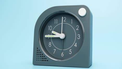 the alarm clock is isolated on a blue background, time starts walking at 9 o'clock.