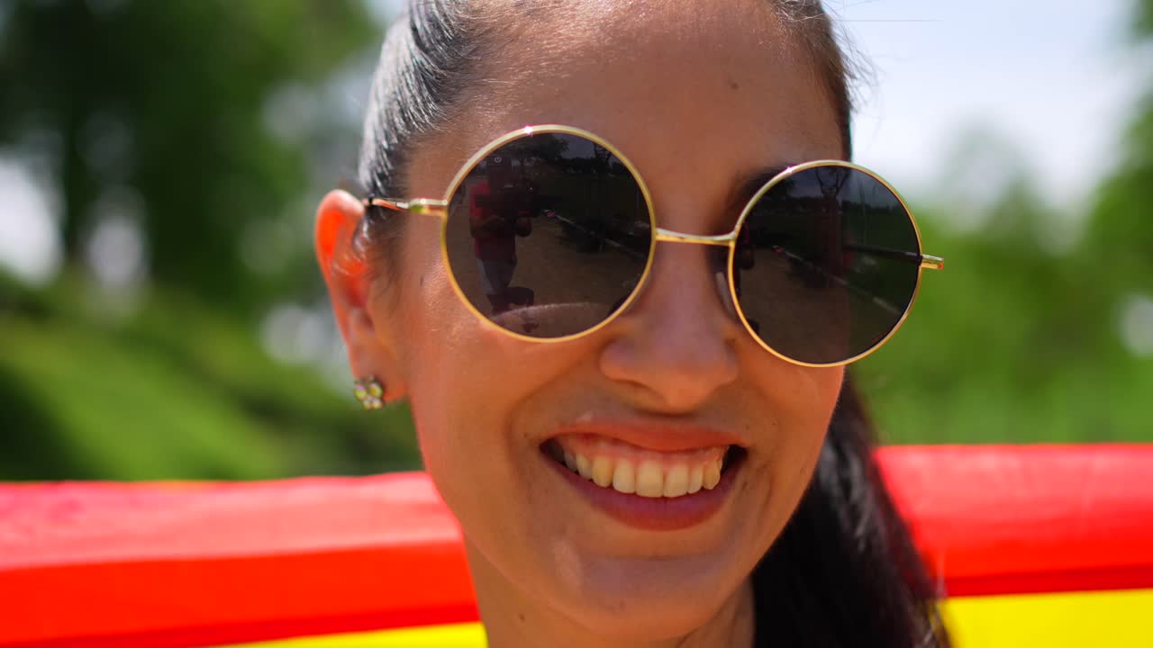 Young woman celebrating LGBTQ pride with rainbow flag in a park