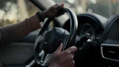 Close-up-of-the-hands-of-a-confident-male-businessman-with-Black-skin-color-that-he-holds-on-the-steering-wheel-during-his-business-trip-in-a-modern-car-in-the-city