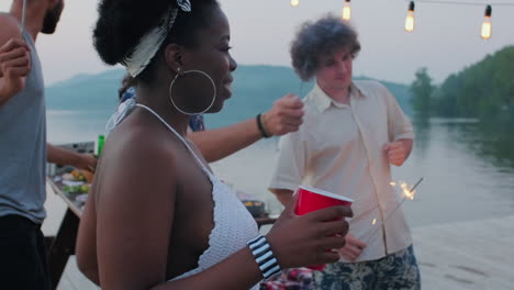 smiling afro-american woman dancing at lake party with friends