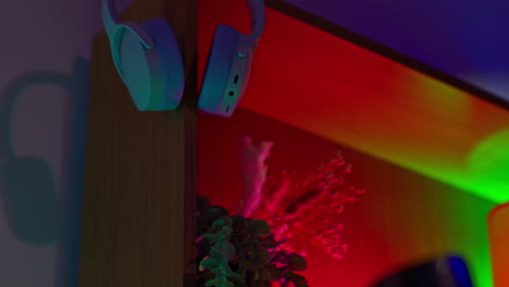 close-up of a shelf with headphones, plants, and colorful lighting