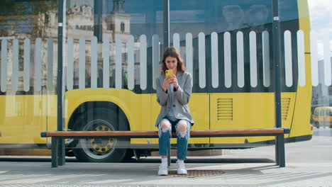 young woman using smartphone at bus stop