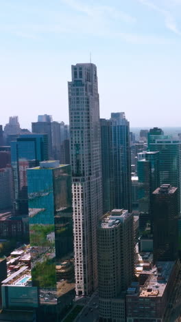 chicago skyscrapers at the waterfront of lake michigan. blue water and skies reflecting in the mirrors of high buildings. vertical video