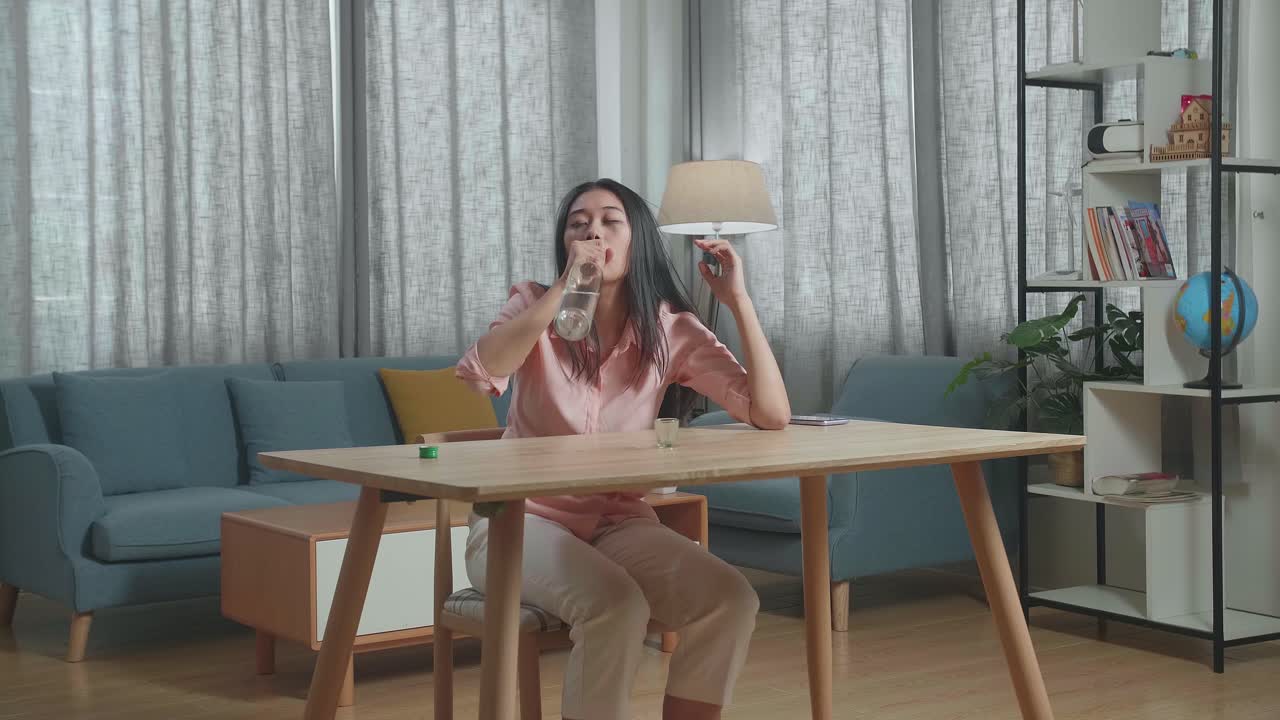 술에 취한 우울한 아시아 여성이 집에서 병에서 보드카를 마시고 있습니다.