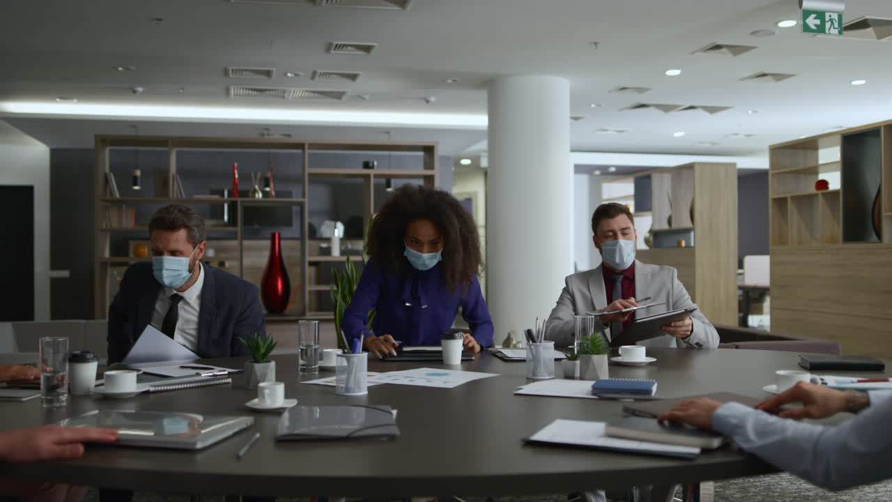Entrepreneurs finish conference meeting leaving office wearing covid face masks.