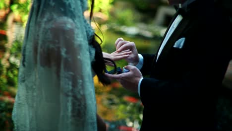 couple exchanging rings during a wedding ceremony in a garden