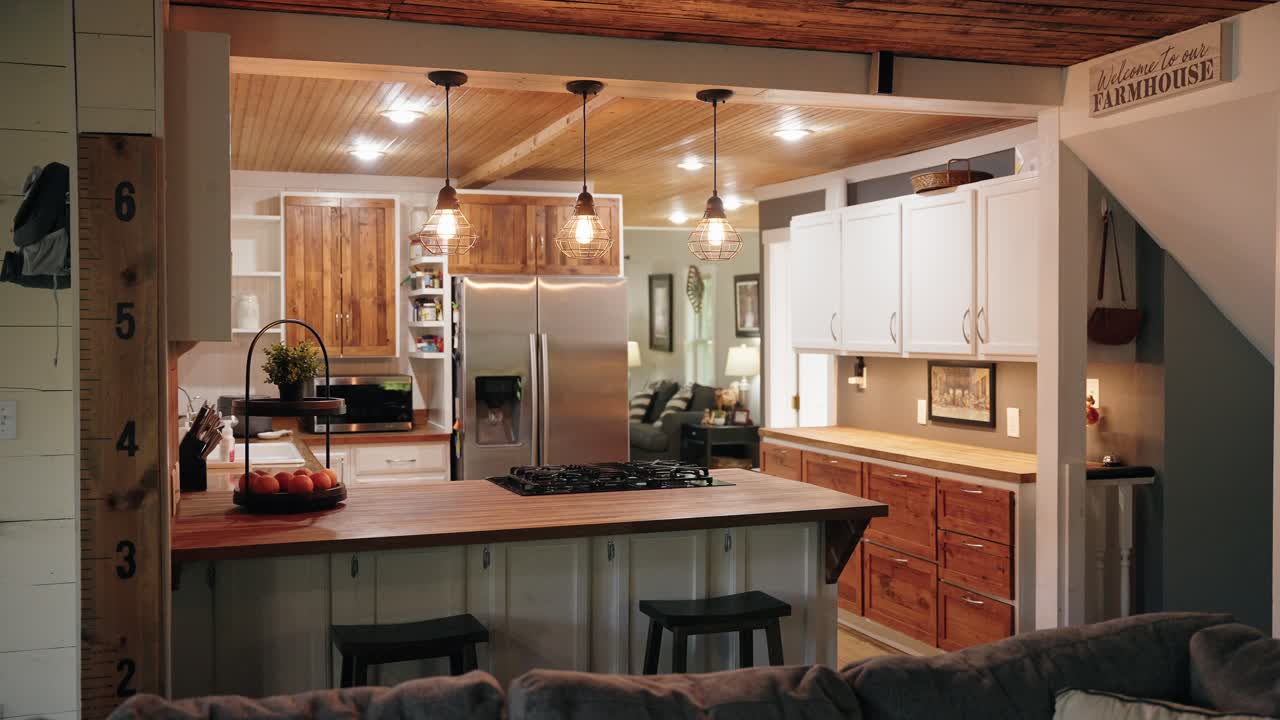 Ripresa panoramica di una cucina di casa colonica con finiture bianche moderne e dettagli in legno.