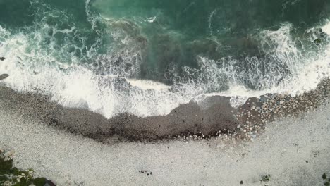 4K-Aufnahmen-Einer-Drohne,-Die-über-Die-Wellen-Fliegt,-Die-Auf-Den-Strand-Treffen,-Und-Still-Bleibt