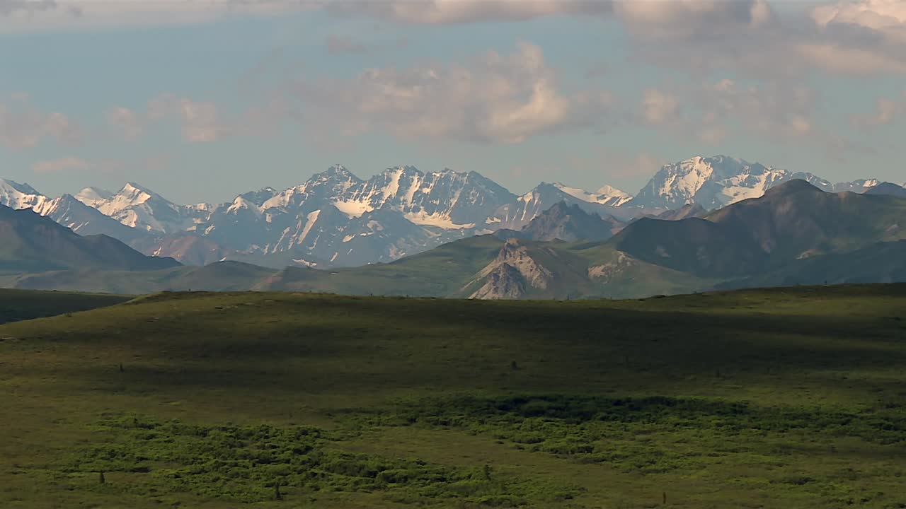 Distant View of Snow-Covered Alaska Range under Partly Cloudy Sky