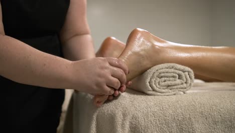masseuse delivering a relaxing foot massage to a woman on a massage table