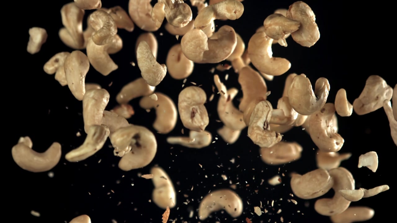 Cashewnøtter som flyr opp i sakte film på svart bakgrunn