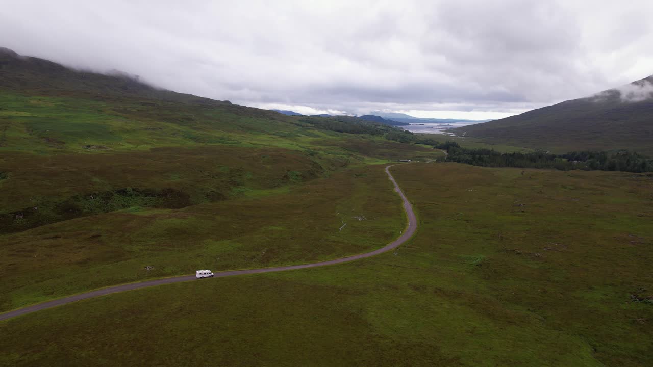 구름이 가득한 하늘 아래 스코틀랜드의 외 녹색 언덕을 가로질러 휘어지는 길