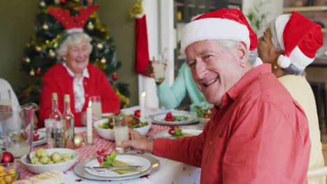 Glücklicher-Kaukasischer-älterer-Mann,-Der-In-Die-Kamera-Blickt-Und-Das-Essen-Mit-Freunden-Zur-Weihnachtszeit-Feiert