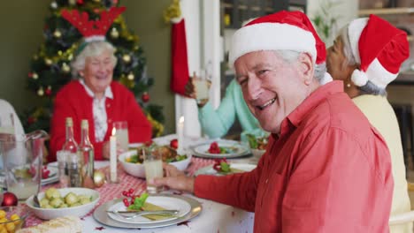 hombre mayor caucásico feliz mirando a la cámara, celebrando la comida con amigos en tiempo de navidad