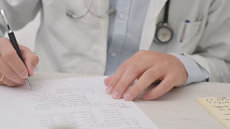 Doctor-With-A-Stethoscope-Hanging-On-His-Neck-Writes-On-A-White-Paper