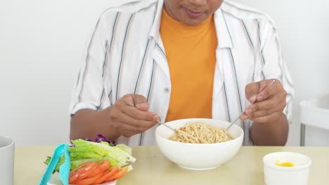 un joven olfateando y agitando deliciosos fideos hervidos en un cuenco con expresión feliz