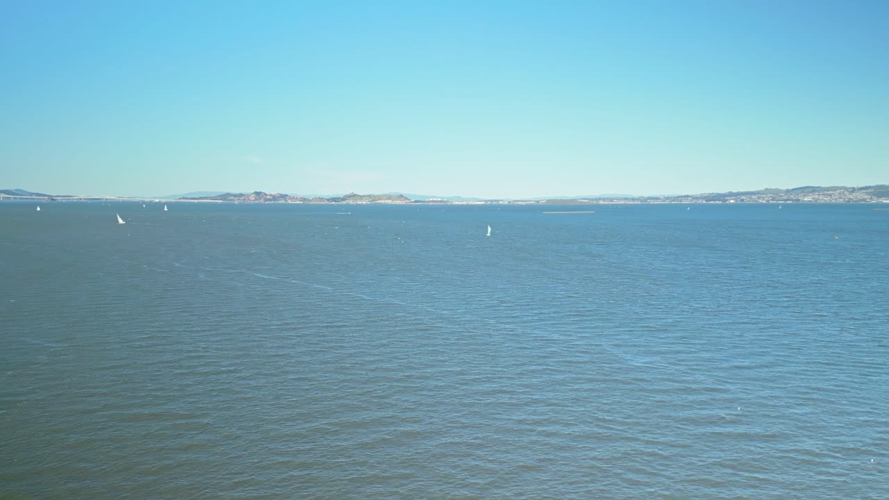 Pan drone shot of Pacific Ocean and Treasure Island with blue sky in California, USA