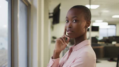 portrait of african american creative businesswoman touching face, looking at camera