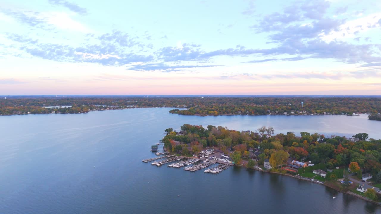An aerial perspective captures Lake Minnetonka surrounded by vibrant fall foliage on a peaceful autumn day
