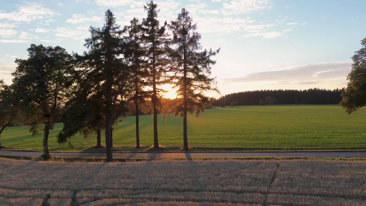 해가 지고 지나가는 차에서 멀어지는 필드 위를 날아다니는 드론 뷰