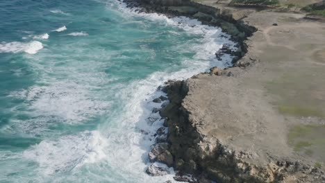 Vista-De-Pájaro-En-ángulo-Alto-De-Las-Fuertes-Olas-Del-Océano-Rompiendo-En-Aguas-Azul-Turquesa-En-La-Costa-Rocosa