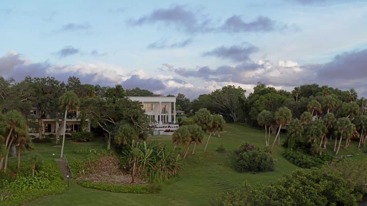 해질녘에 현대적인 고급 주택에서 드론이 호수 위로 천천히 끌어옵니다.