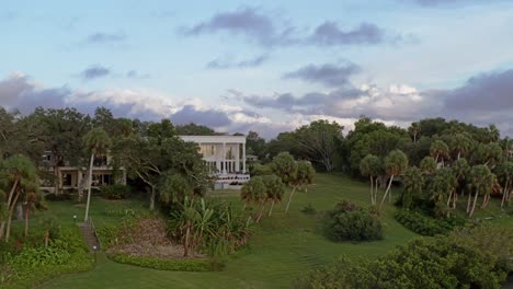 el dron retrocede lentamente sobre el lago desde una casa de lujo moderna al atardecer