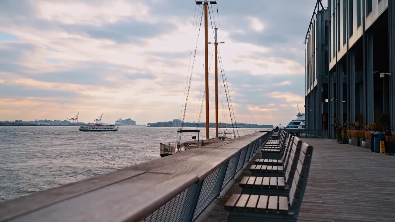 Promenade am Hudson River am Wasser. Leere Bänke säumen eine moderne Uferpromenade entlang des Hudson River bei Sonnenuntergang