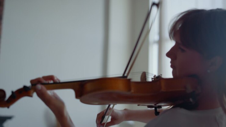 Donna che suona una composizione musicale al violino. Ragazza attraente che usa l'archetto del violino.