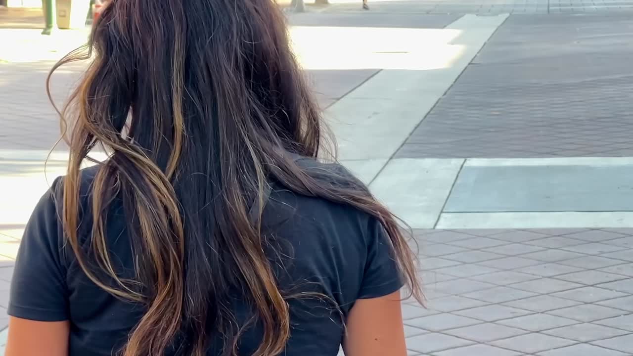 도시 외부에서 걷고 있는 히스패닉 여성의 뒷모습, 돌아서서 카메라를 향해 미소 짓는 모습