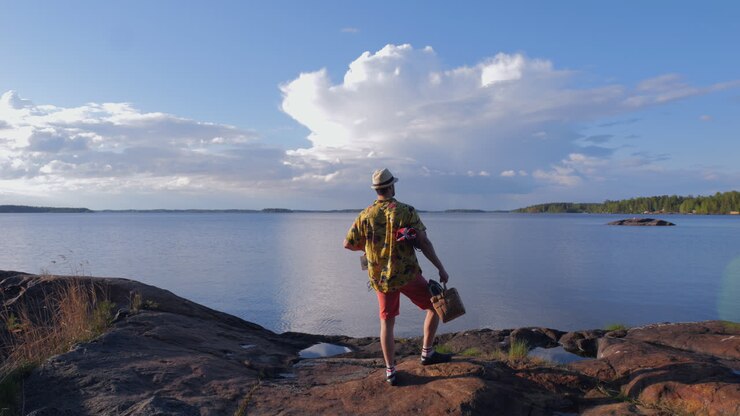 Un touriste amusant, vêtu d'une chemise et d'un short colorés et vifs, marche vers la mer.