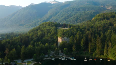 green forest and dockyard at the waterfront of bohinj lake with a view of the mountain range in slovenia