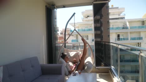 mujer trabajando en una computadora portátil en un balcón con vista a la ciudad