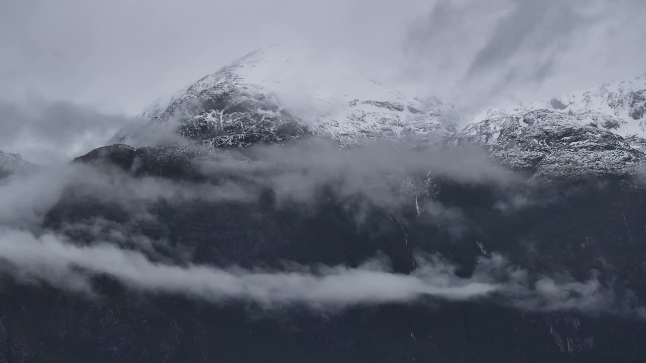 Snow-capped mountains shrouded in mist and clouds