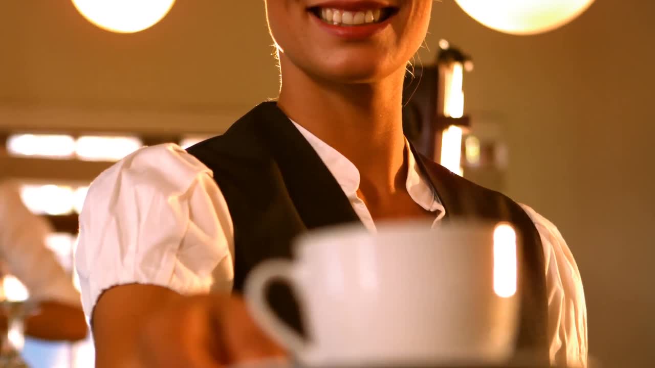 Mid-section of female waitress serving a cup of coffee