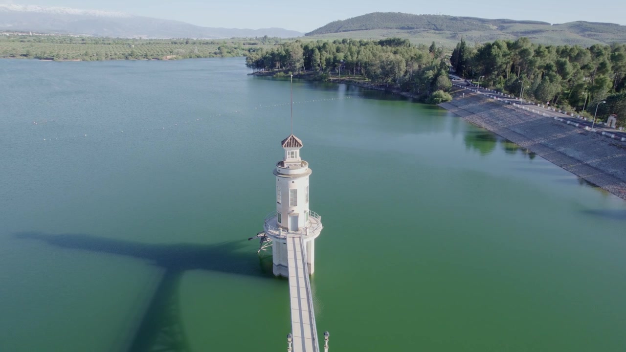 Turm und Steg über dem See. Höhenflug über einen Steg in türkisfarbenem Wasser. Orbitale Luftaufnahme. Cubillas-Stausee. Spanien.